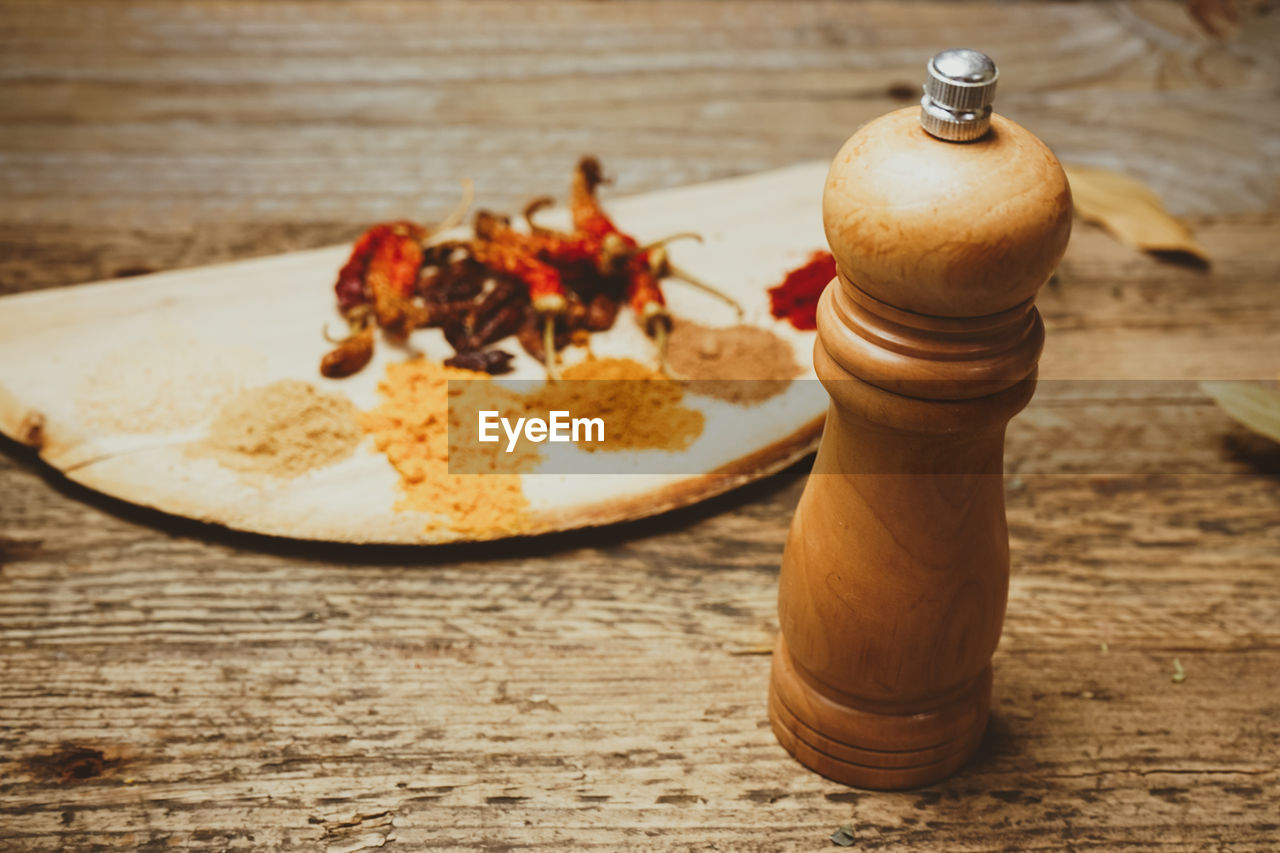 Wooden pepper mill by spices on table