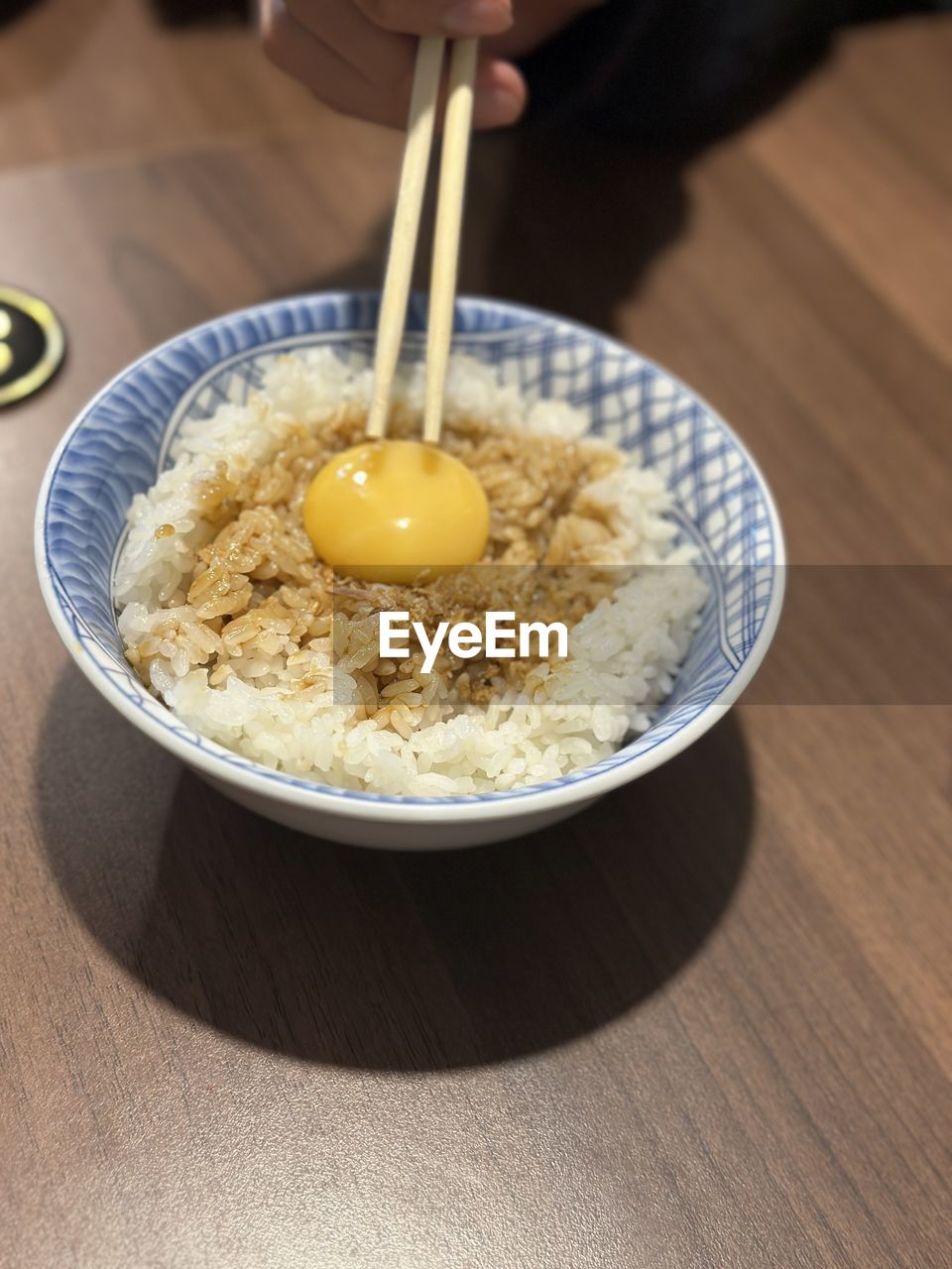 food and drink, food, dish, one person, indoors, hand, egg, bowl, meal, breakfast, freshness, healthy eating, wellbeing, table, kitchen utensil, high angle view, wood, holding, egg yolk, adult, produce, close-up, lifestyles, cuisine