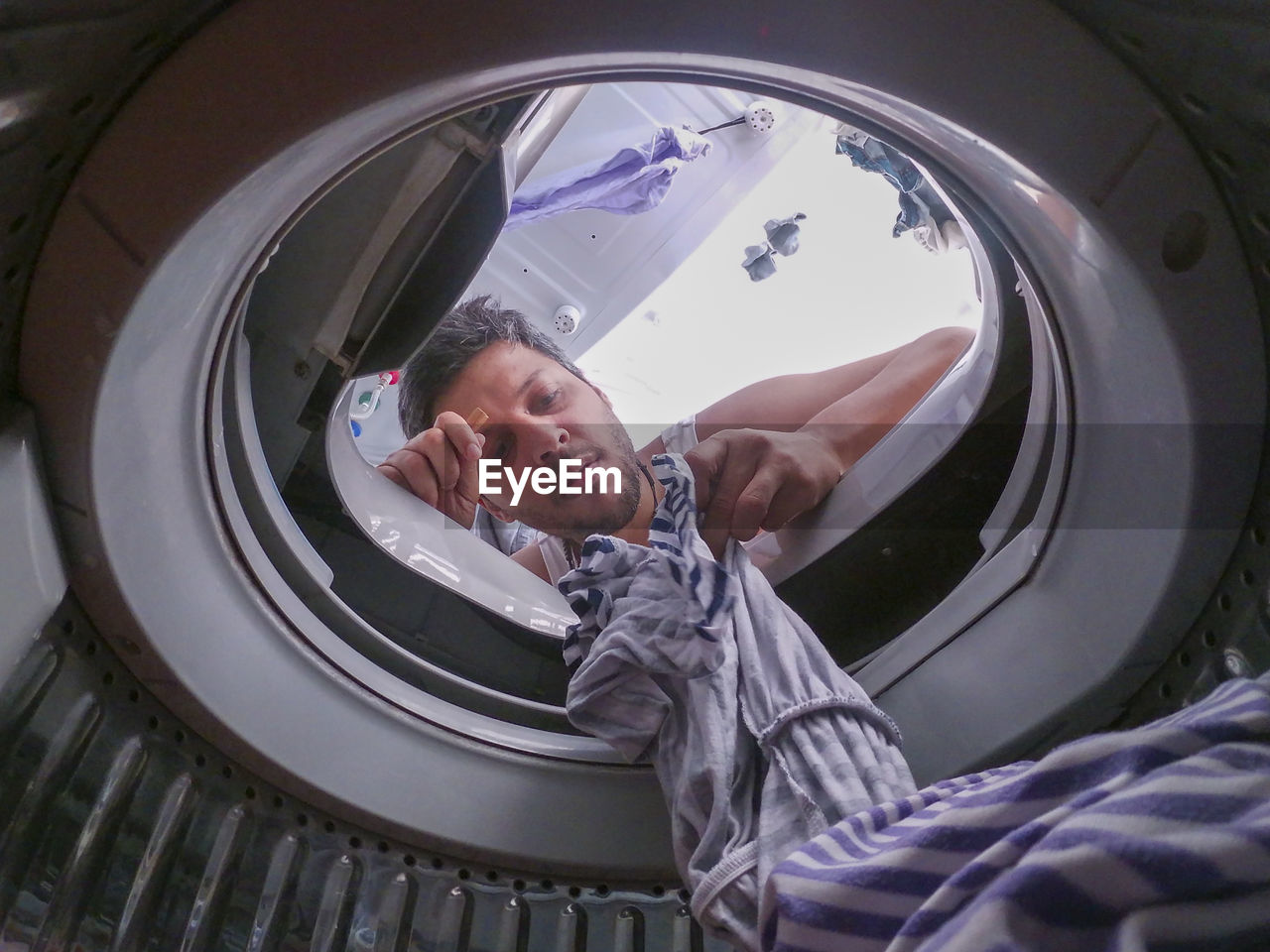 Low angle view of man removing clothes from washing machine