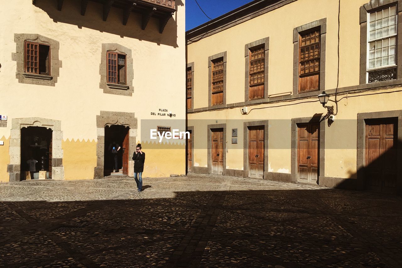 WOMAN WALKING ON STREET BY BUILDINGS IN CITY