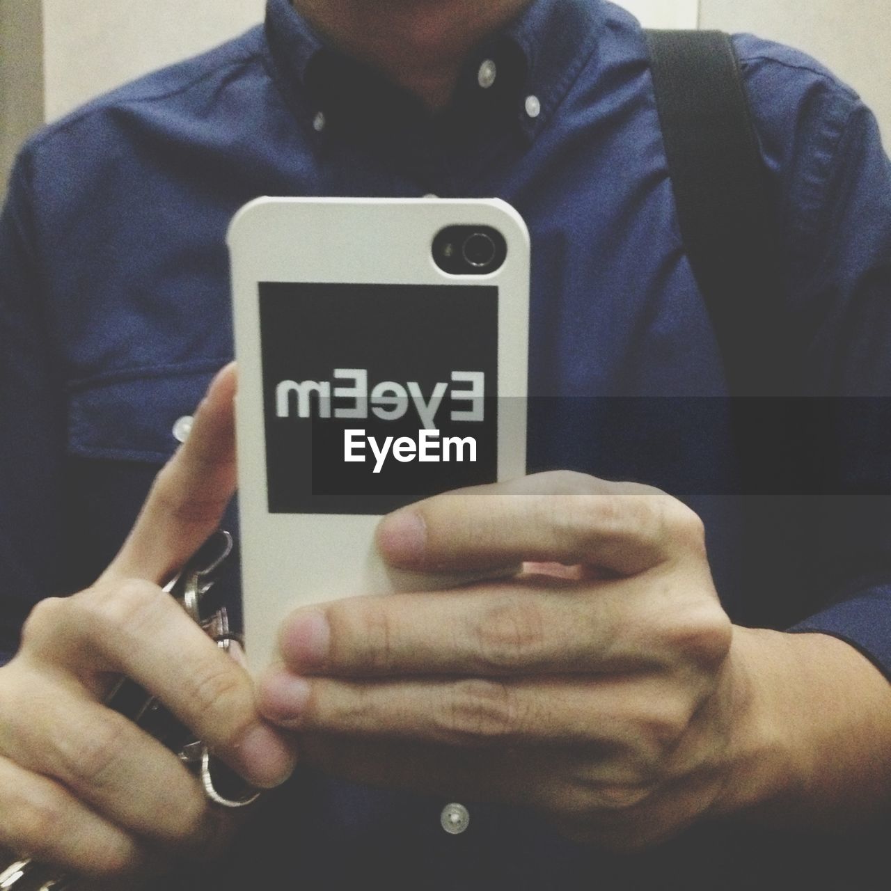 Midsection of man holding smart phone with eyeem text