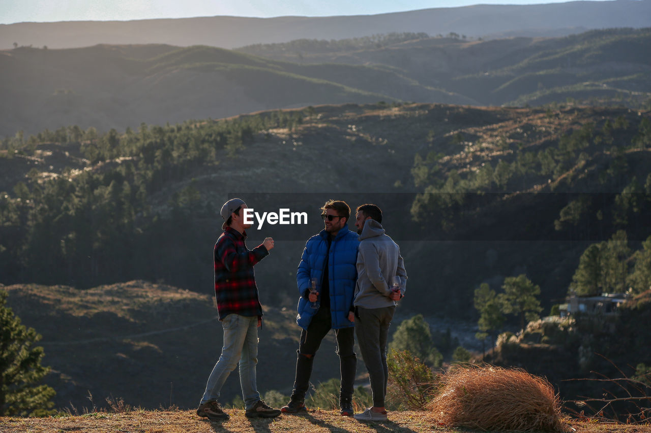 Rear view of man standing on mountain, friends having a good weekend