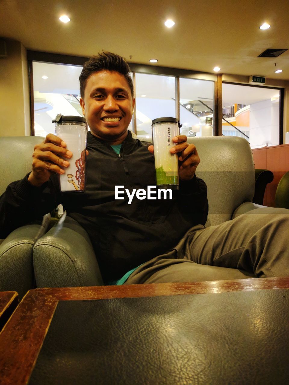 PORTRAIT OF HAPPY YOUNG MAN USING LAPTOP IN RESTAURANT