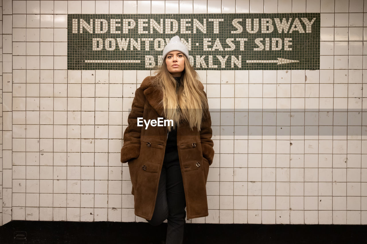 Portrait of young woman standing against text onn wall