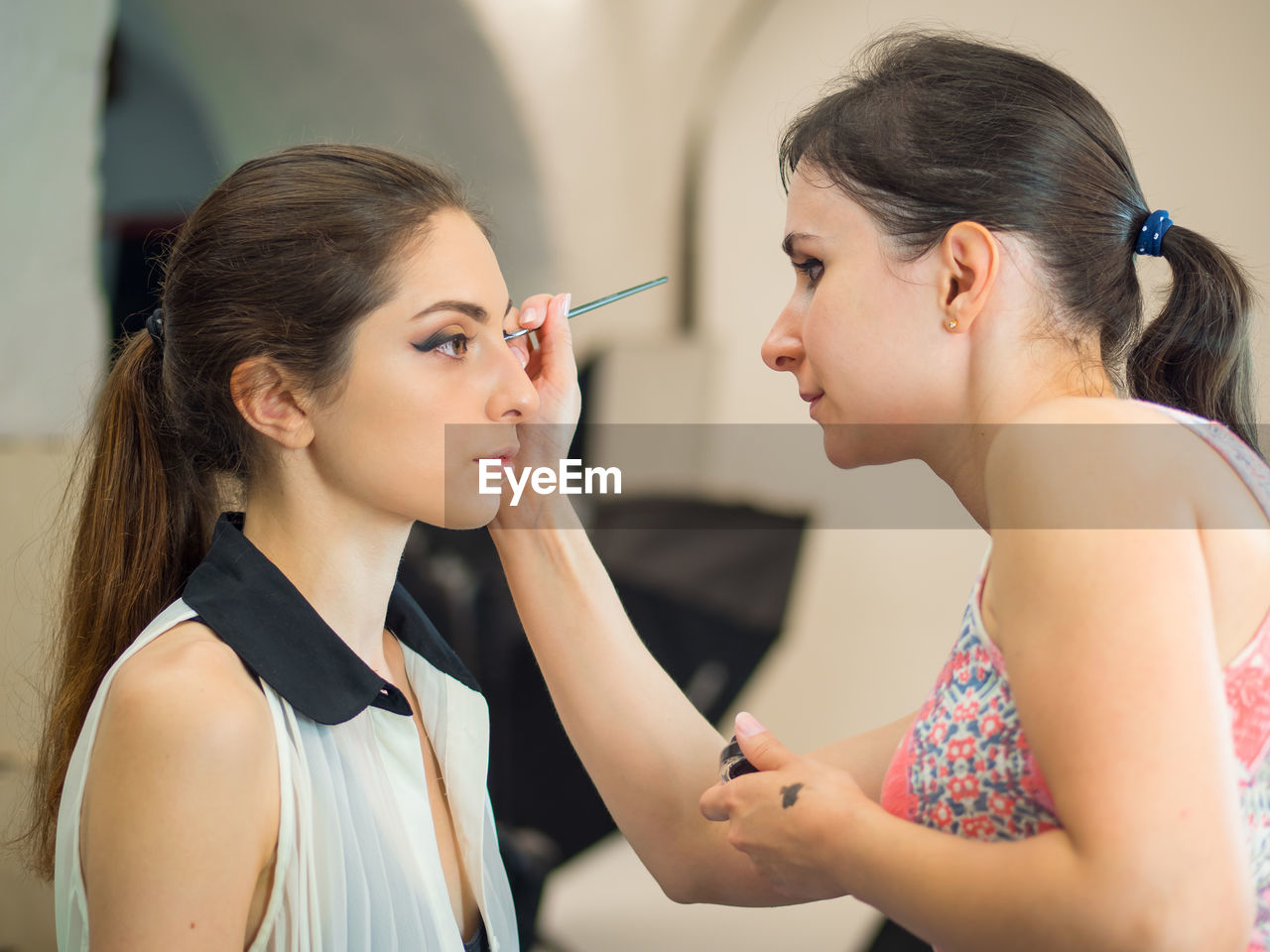 Artist applying make-up on woman in beauty spa