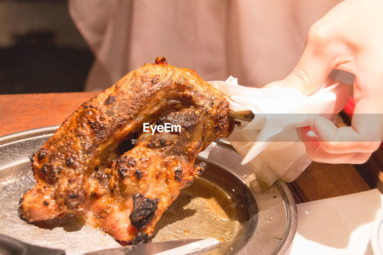 Close-up of womans hand holding roast chicken