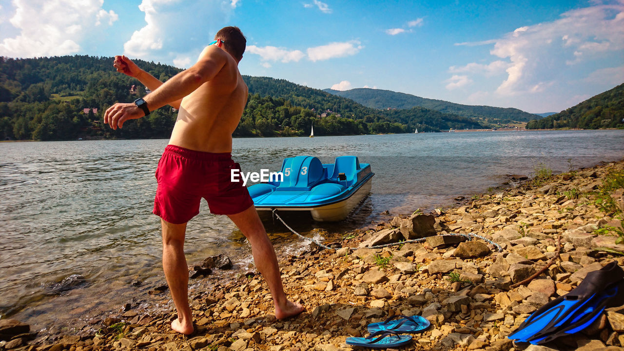 Full length of playing man standing on beach against sky