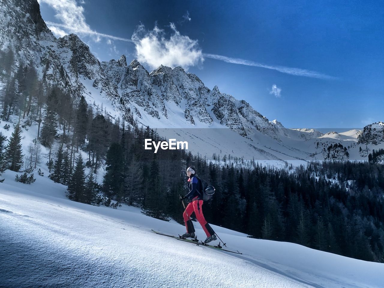 Woman walking on snowcapped mountain against sky