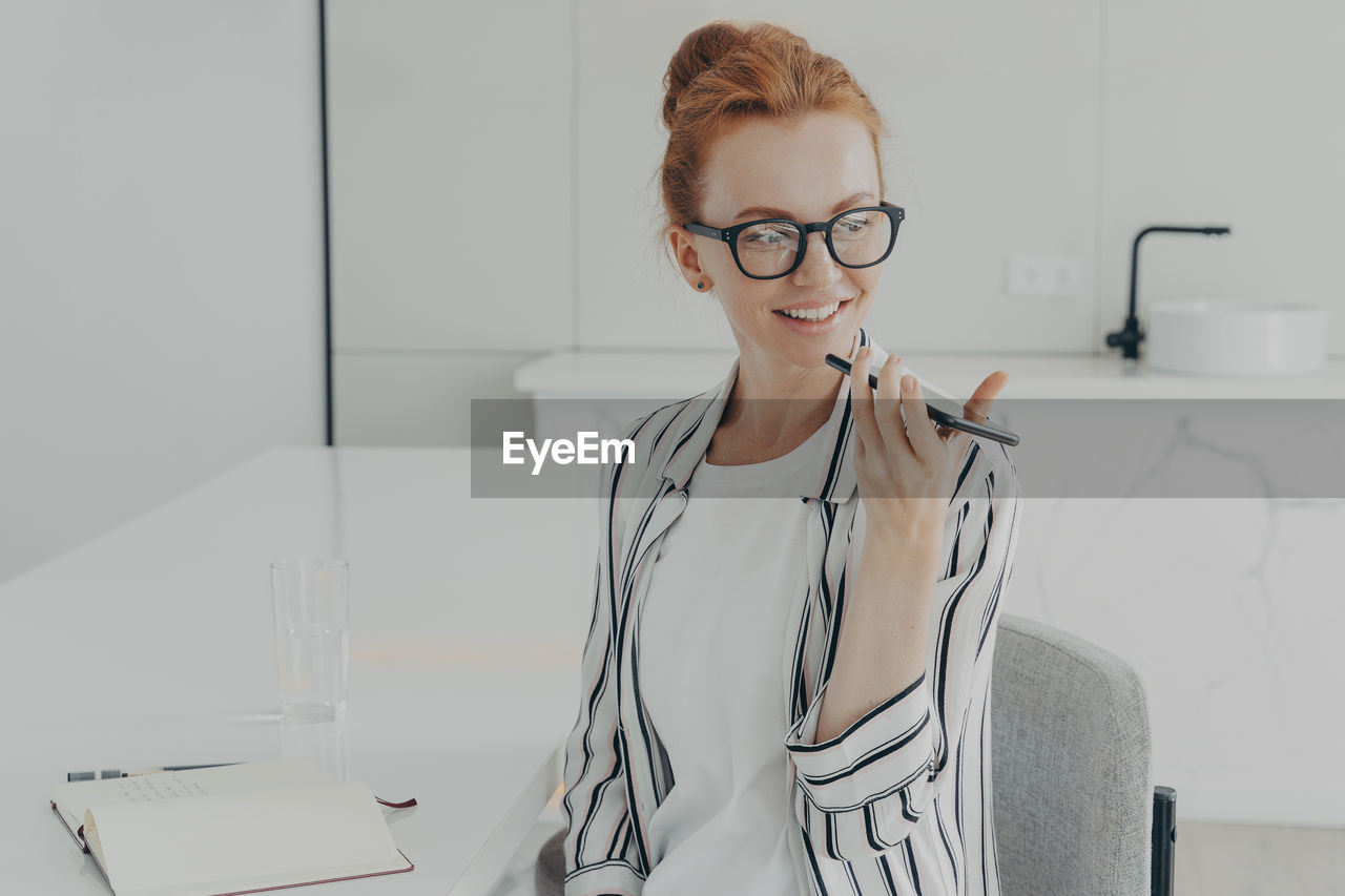 PORTRAIT OF A SMILING YOUNG WOMAN WEARING EYEGLASSES