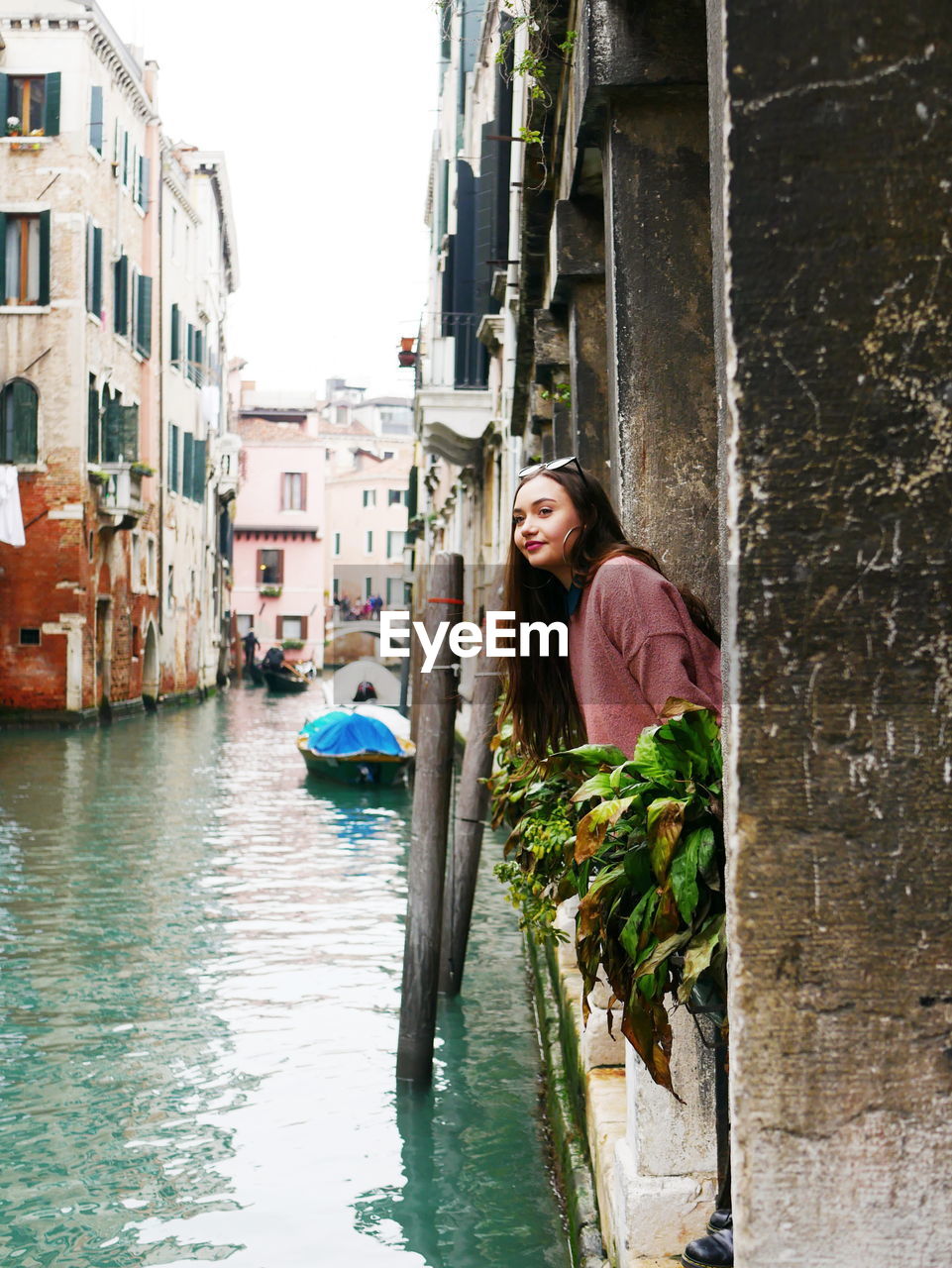 Young woman standing by canal in city