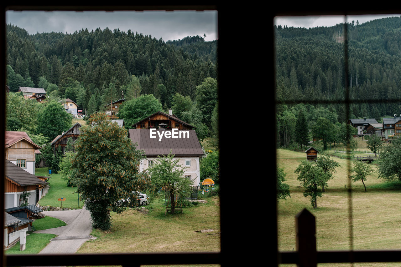 HIGH ANGLE VIEW OF TREES AND BUILDINGS SEEN THROUGH HOUSE WINDOW