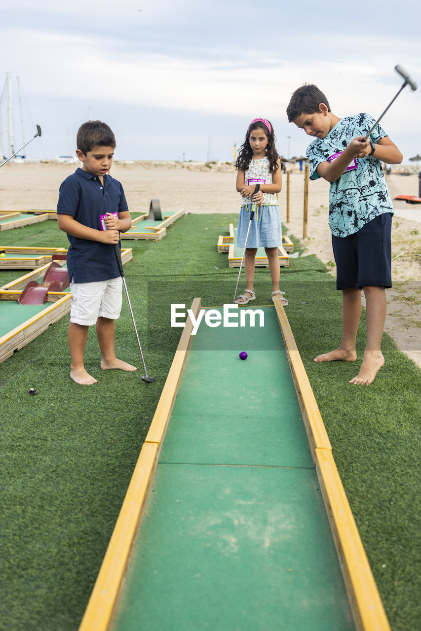 Cute kids playing golf outdoors