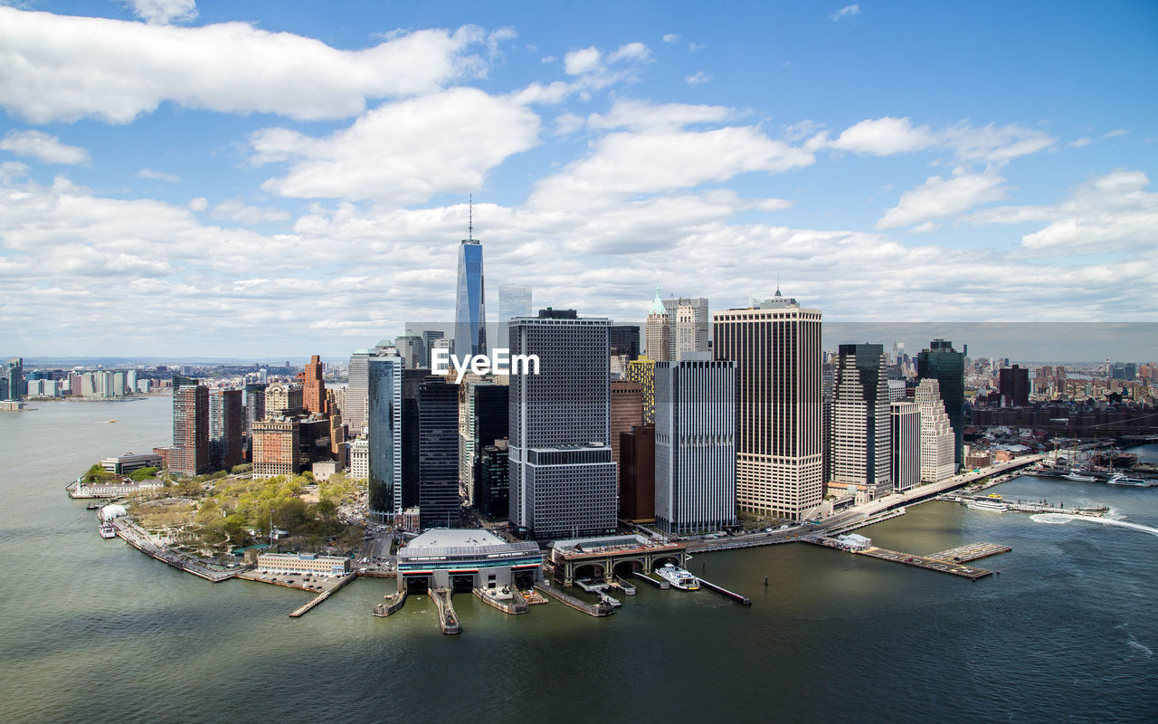 High angle view of east river by modern buildings against cloudy sky