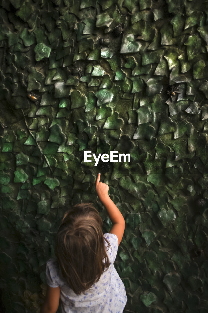 Rear view of girl touching patterned wall