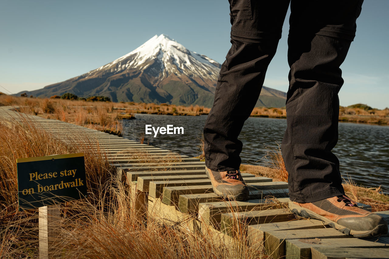 LOW SECTION OF MAN STANDING ON SNOWCAPPED MOUNTAIN