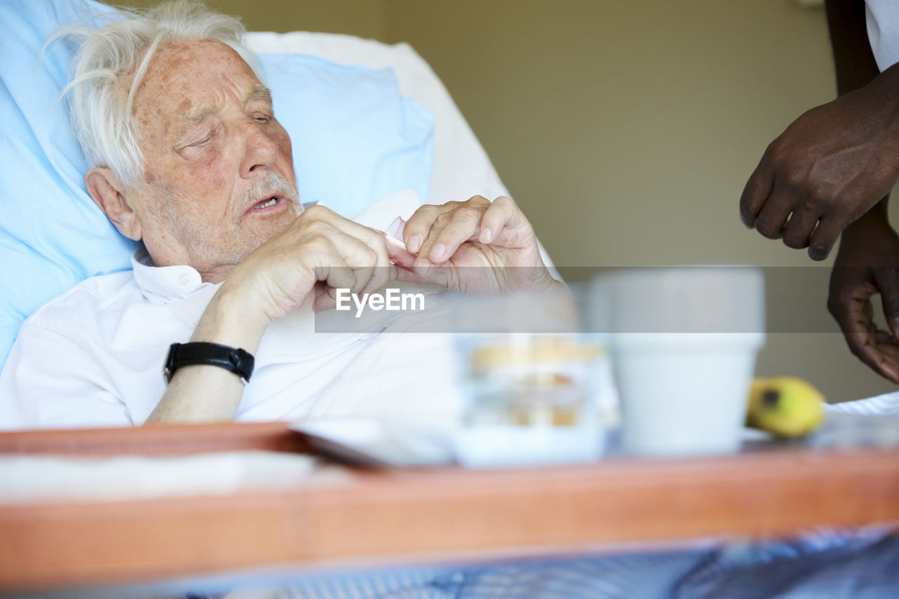 Senior man taking medicine in hospital bed