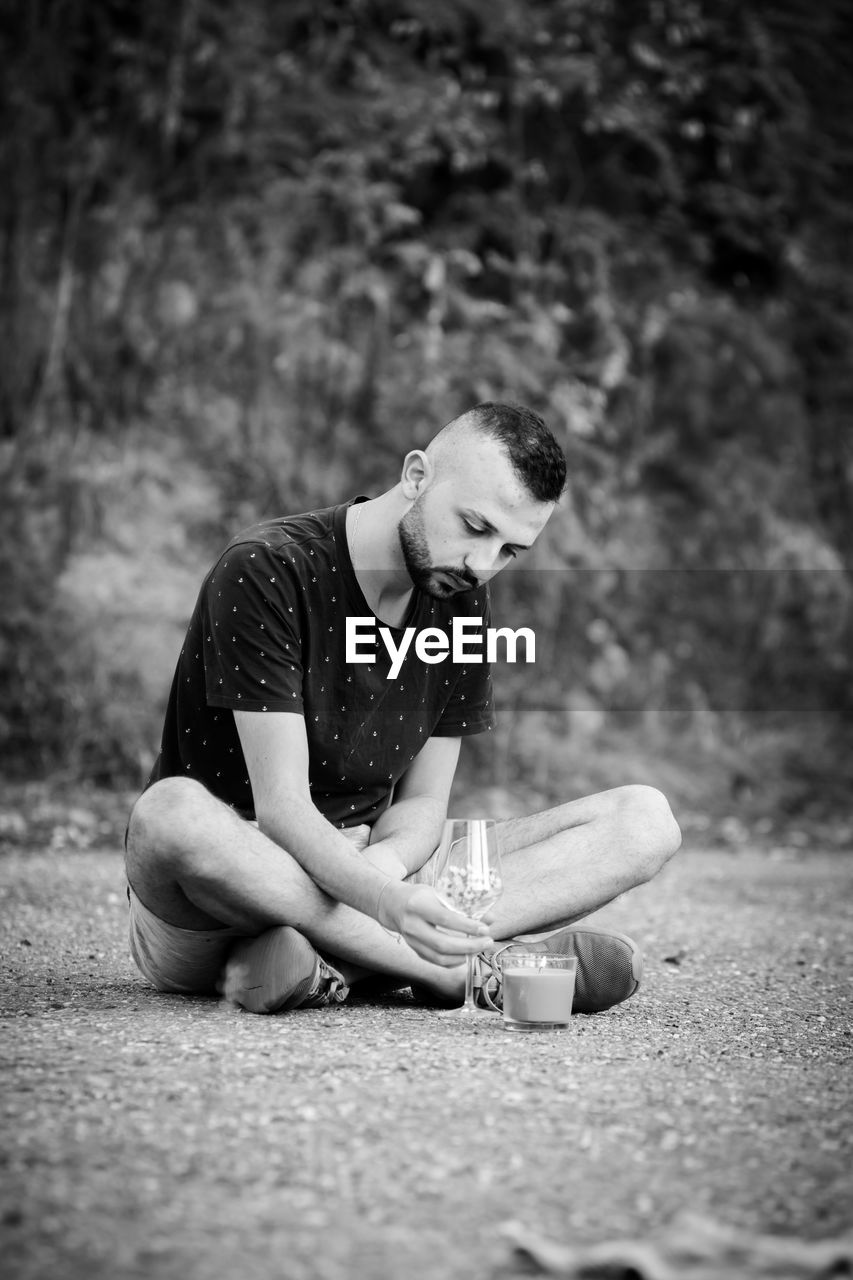 Young man looking away while sitting on land