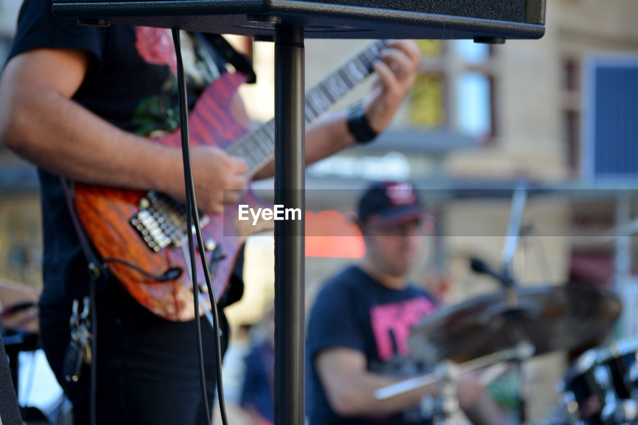 Midsection of man playing guitar on music concert