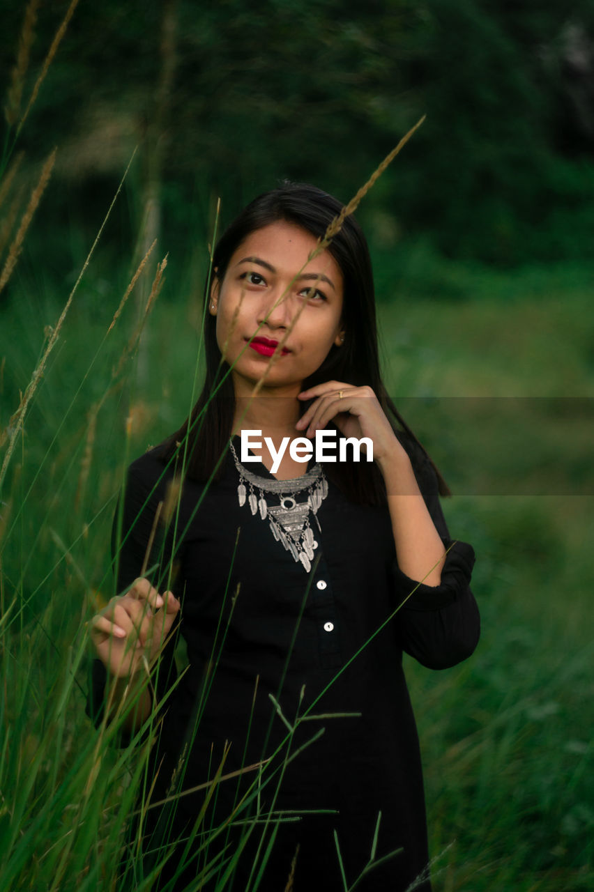 Portrait of young woman standing on field