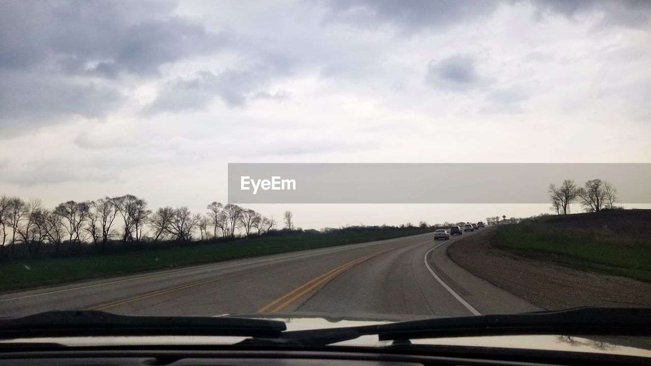 CAR ON ROAD AGAINST SKY SEEN THROUGH WINDSHIELD