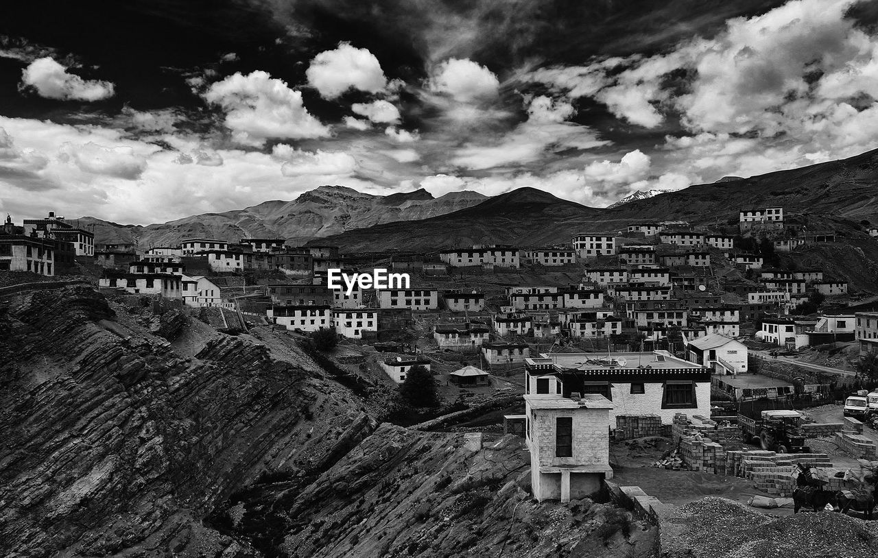 Buildings on mountains against cloudy sky in village
