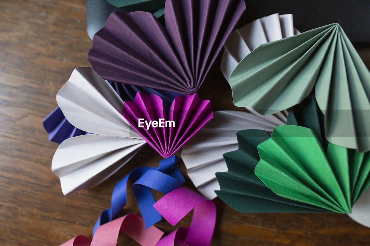 Paper crafts of various colors stacked on wooden surface