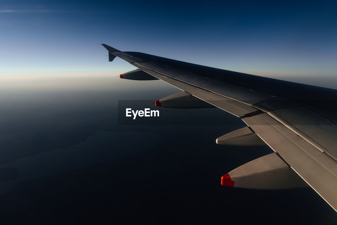 Close-up of airplane flying over landscape against sky