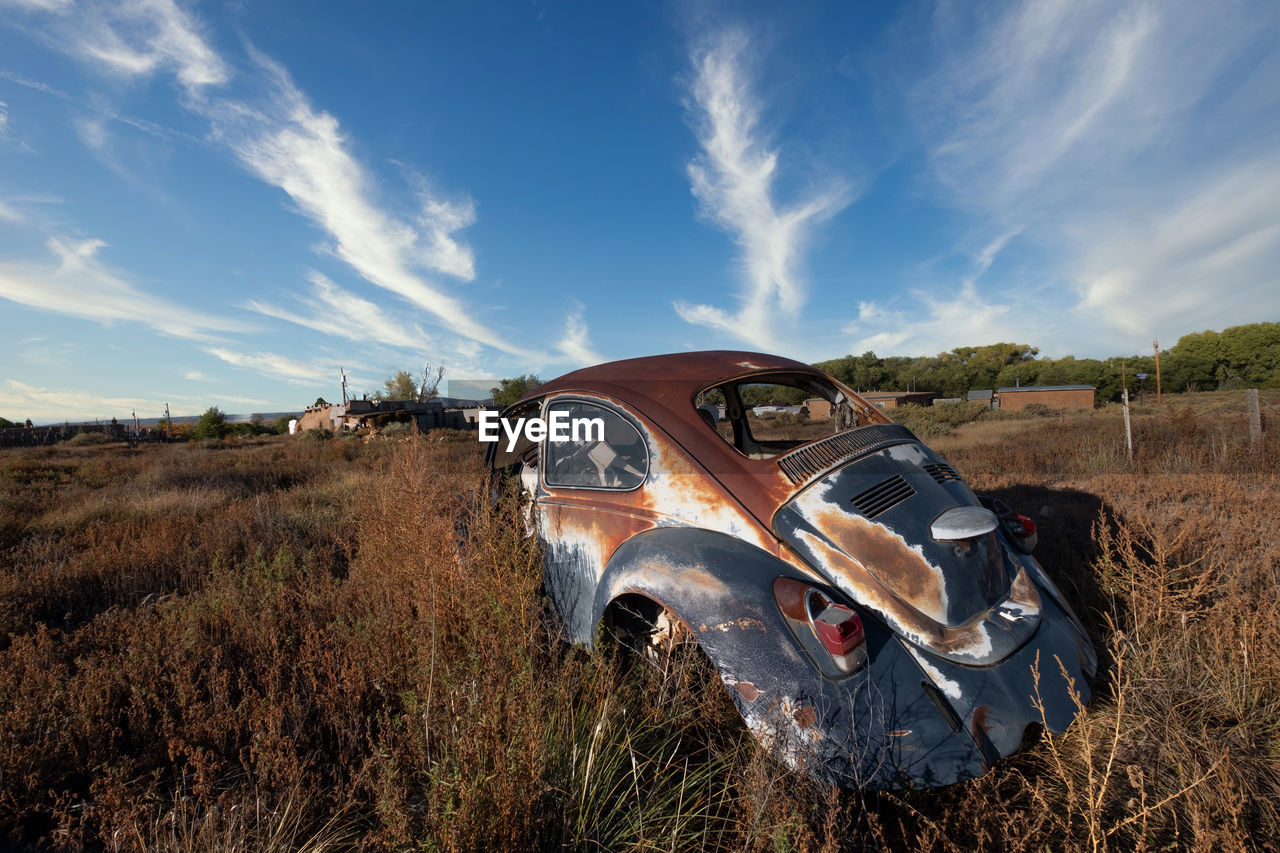 Panoramic view of abandoned car on field against sky