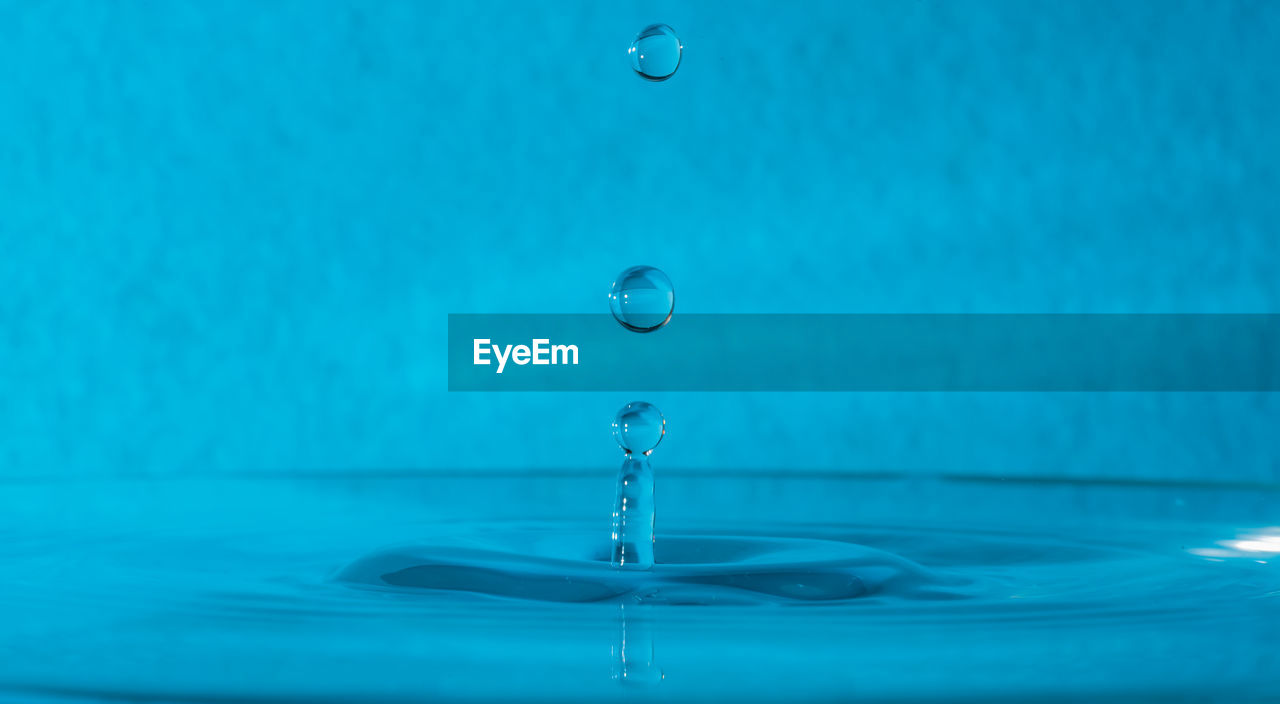 CLOSE-UP OF WATER DROP ON BLUE SURFACE