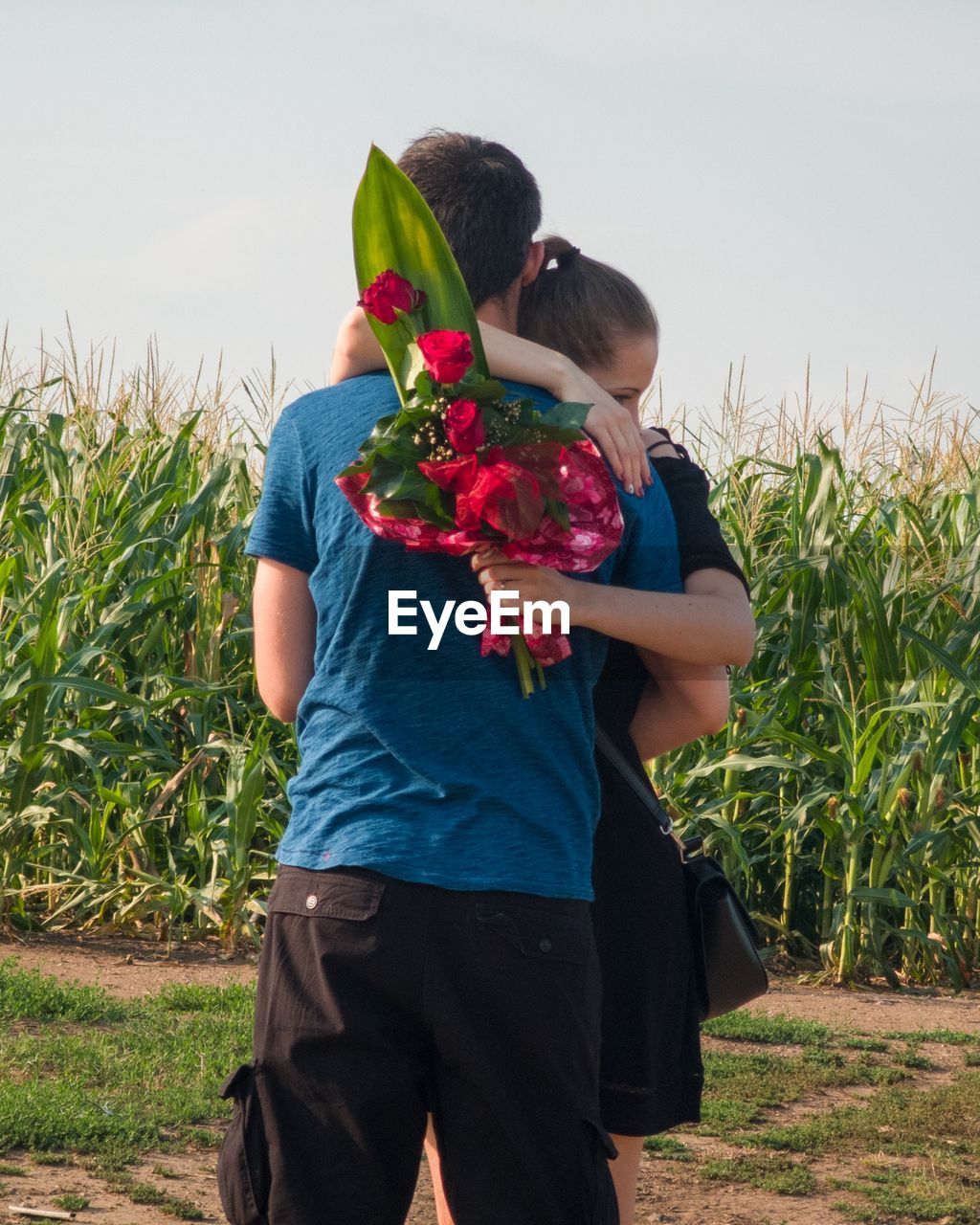 Couple embracing while standing by plants on land