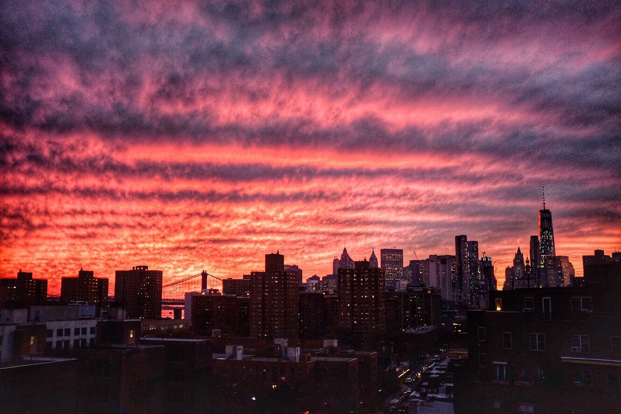 CITYSCAPE AGAINST CLOUDY SKY AT SUNSET