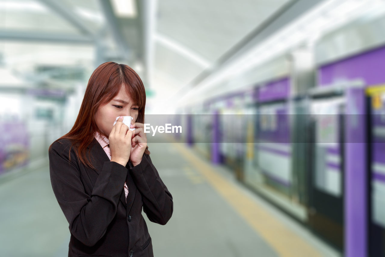 Businesswoman sneezing at railroad station