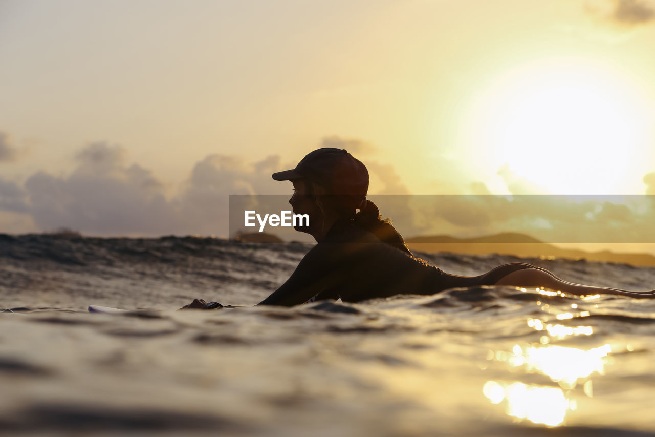 Female surfer lying on surfboard in the evening