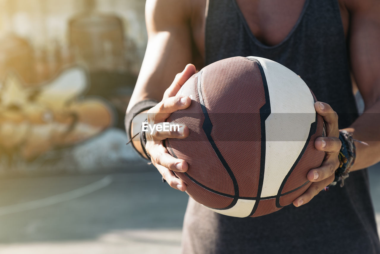 Midsection of man holding basketball