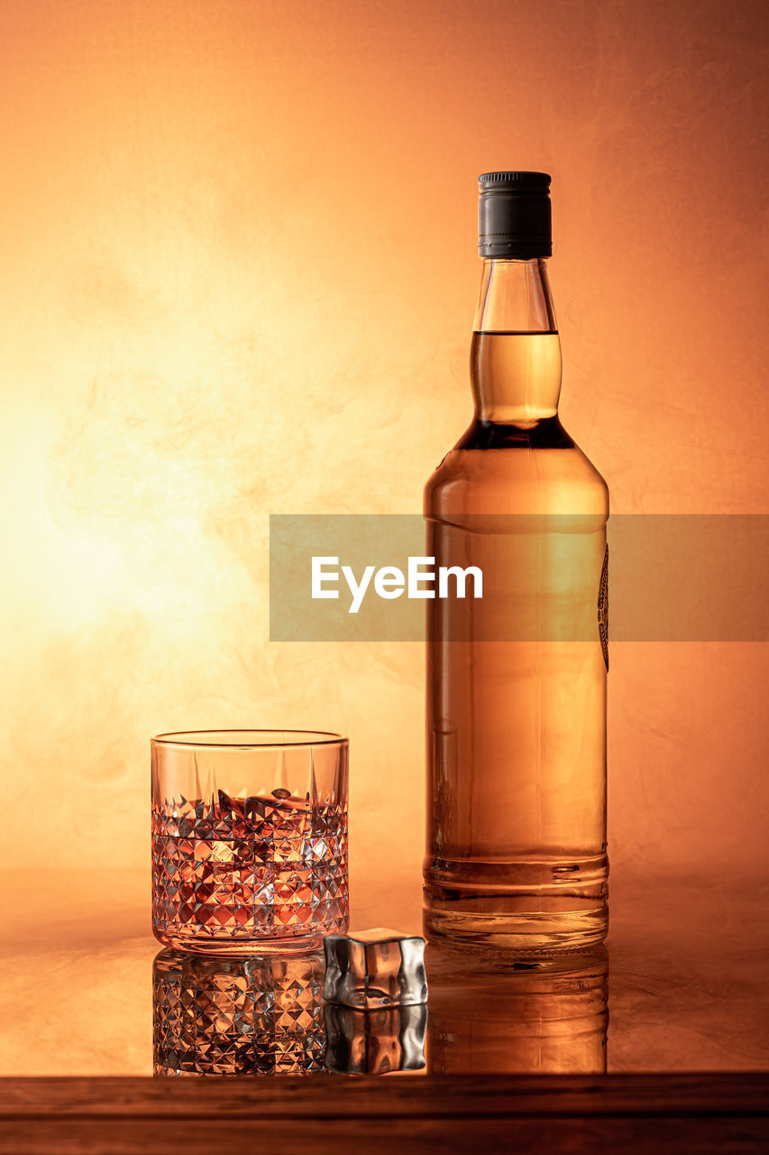 Bottle of whiskey with bright orange smoke background.