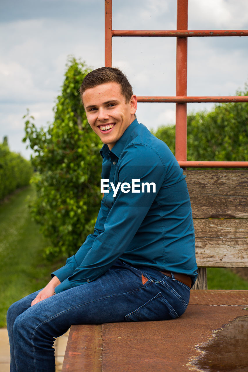 Portrait of happy young man sitting against vineyard