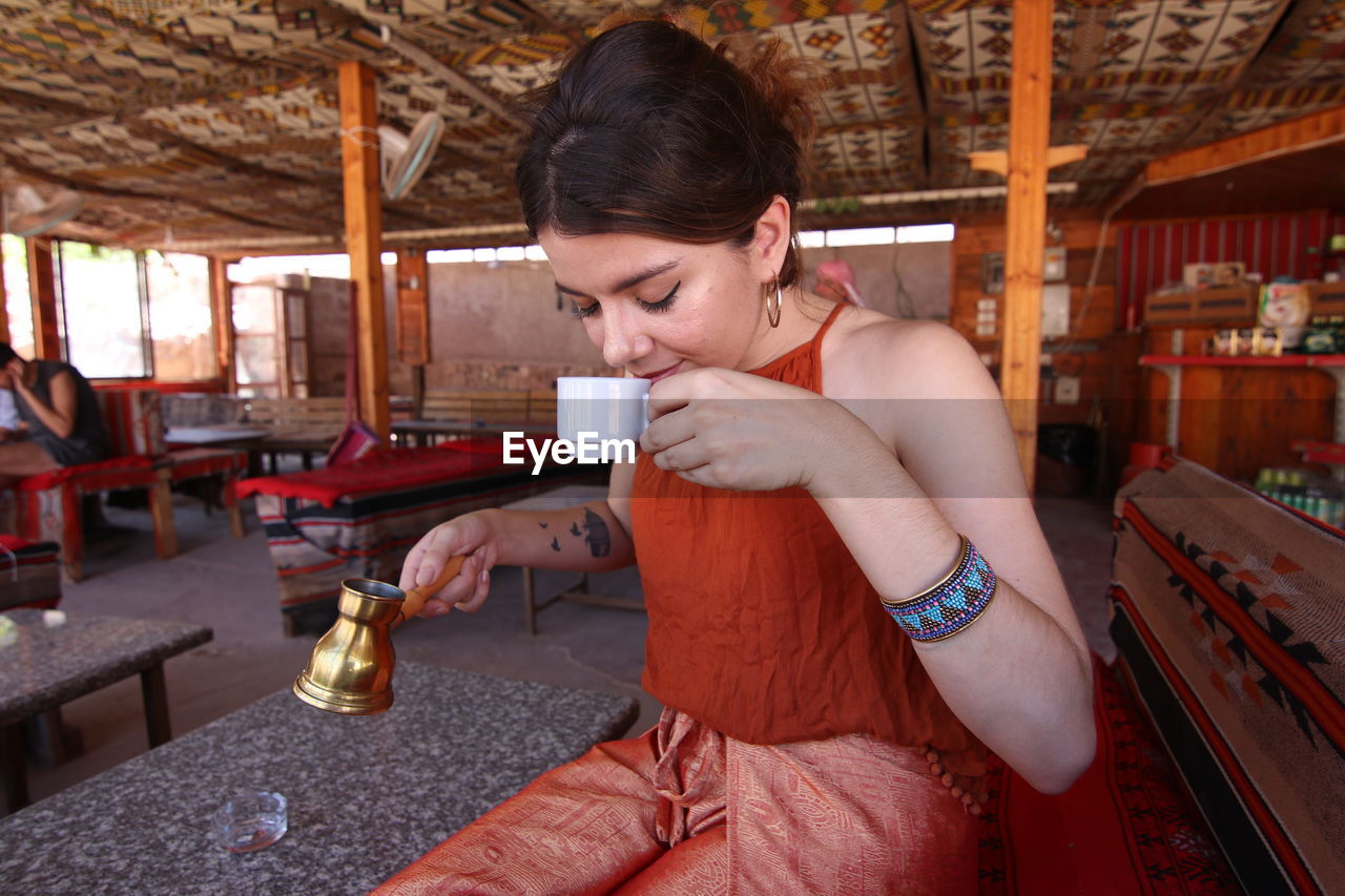 Young woman drinking coffee in tent