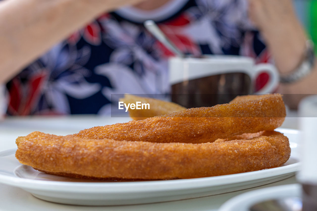 Close-up of some traditional churros, with an out-of-focus person in the background