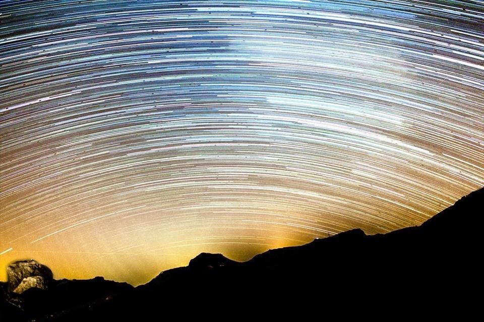 Star trails over silhouette mountains at night