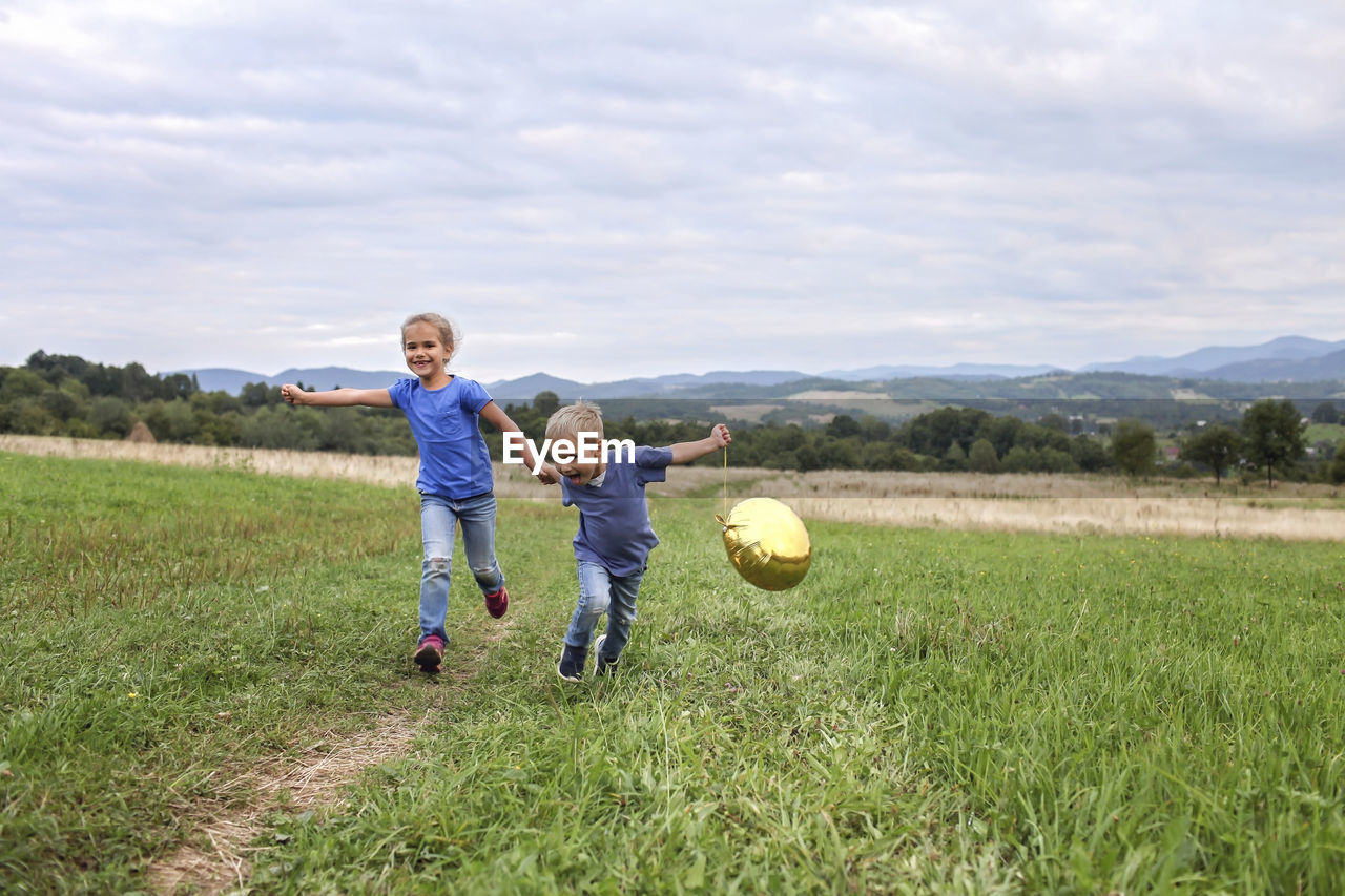 Boy playing with ball on field against sky