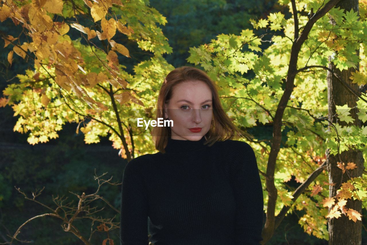 Portrait of young woman standing against plants