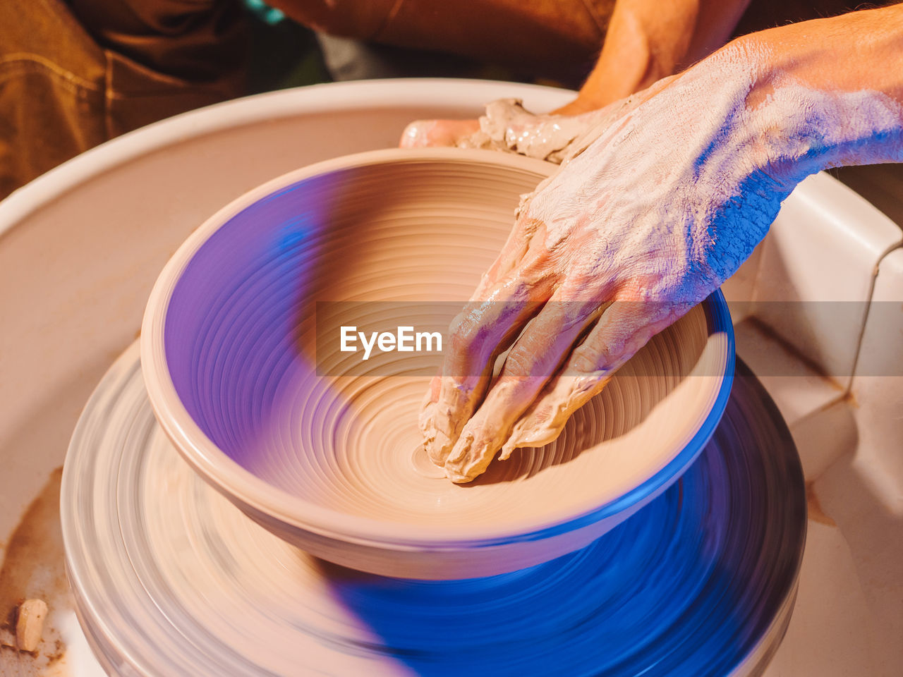 Cropped hand of potter making pot using pottery wheel in workshop