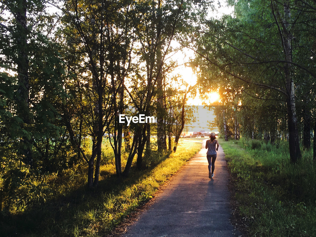 Rear view of woman running on road amidst trees