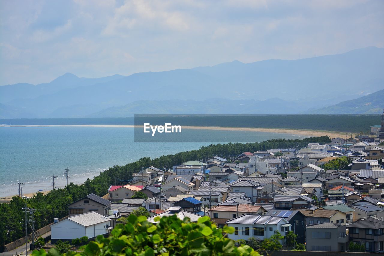 High angle view of townscape by sea against sky and mountains