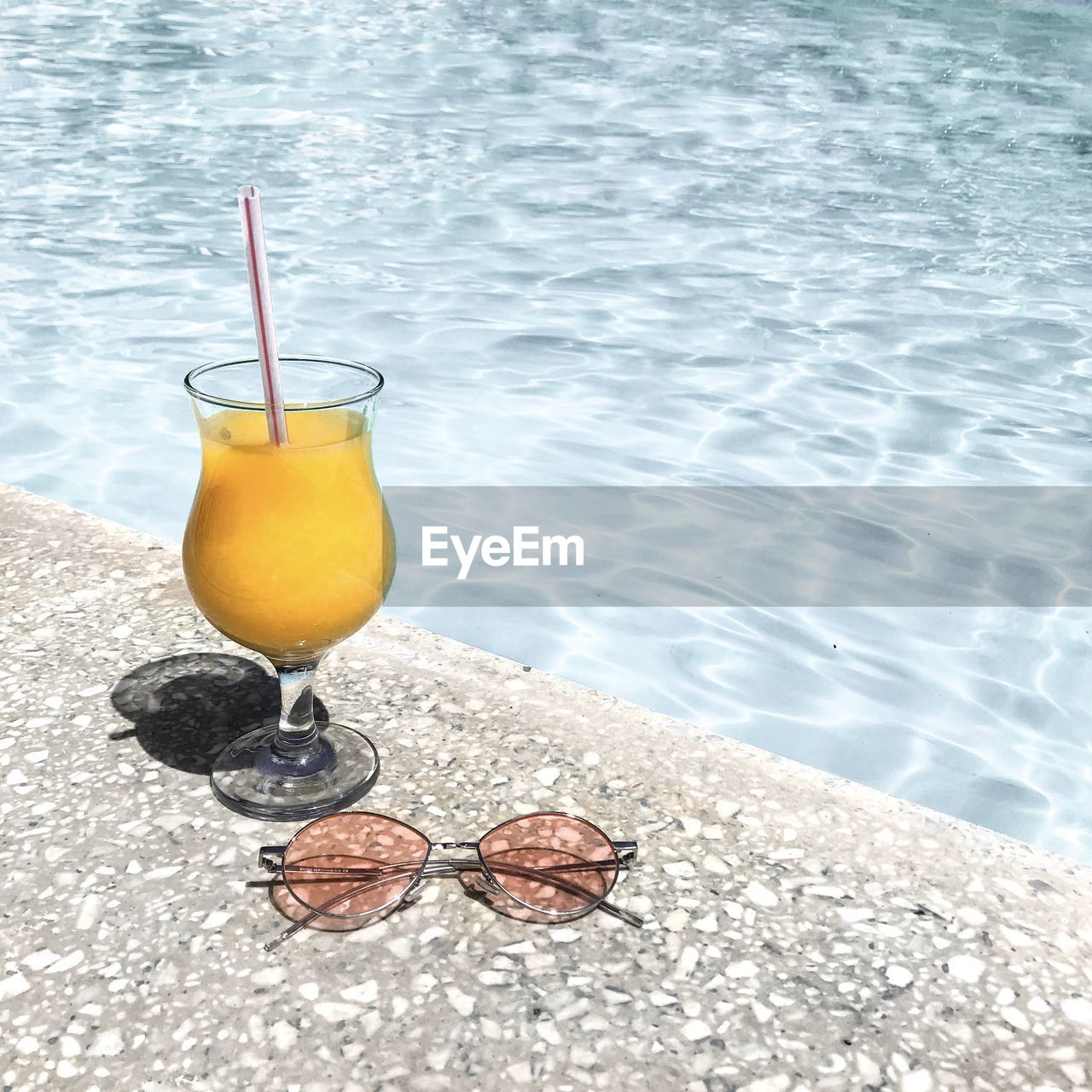 High angle view of drink and sunglasses by swimming pool