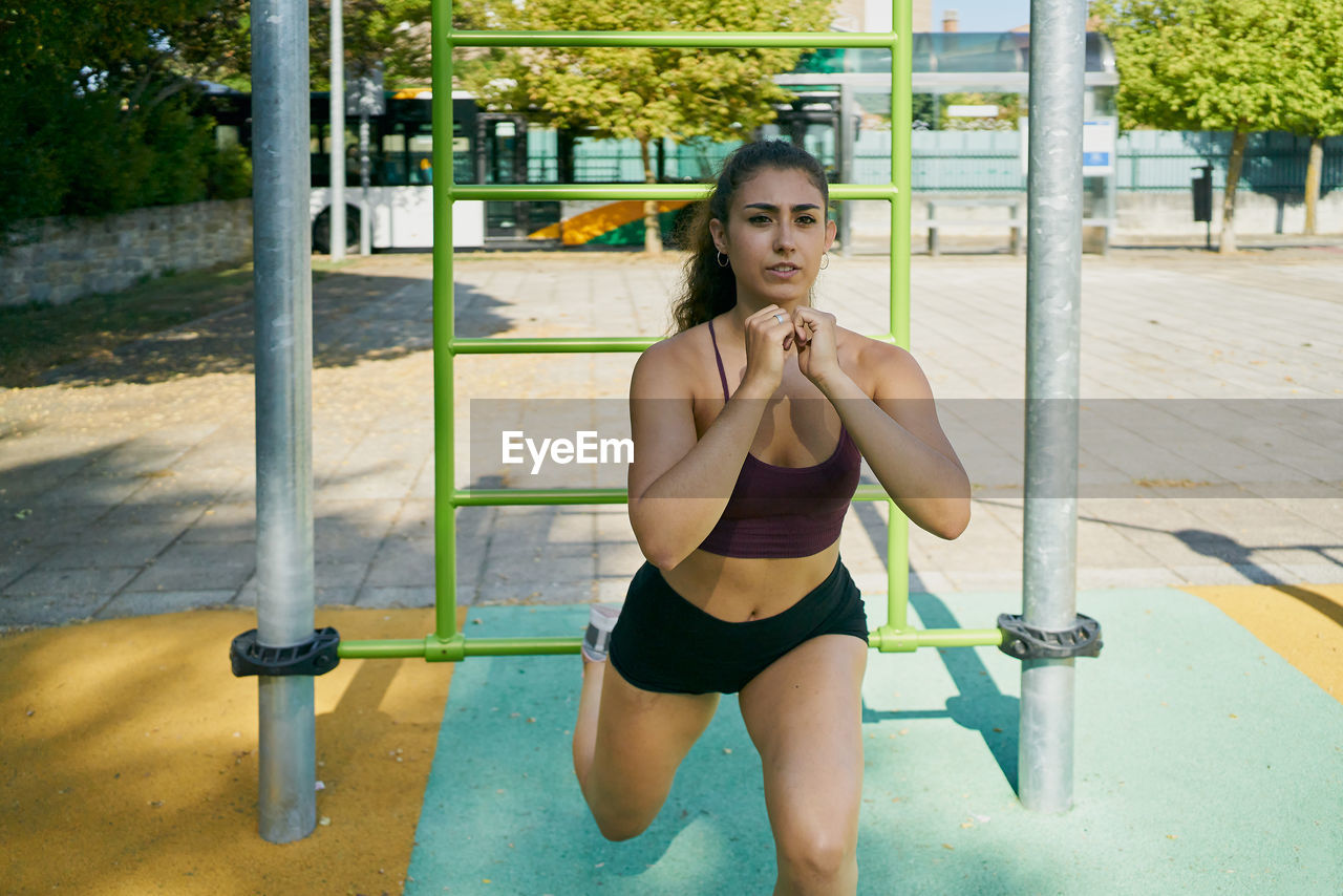 Young woman practicing calisthenics in a park on sunny day