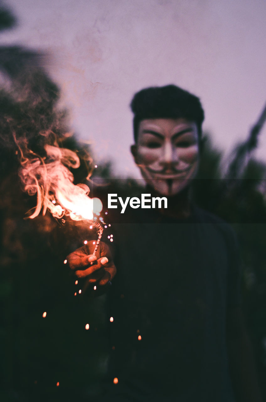 Man wearing mask while holding firework 