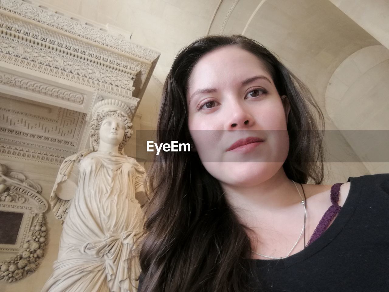 Low angle view of beautiful young woman against statue