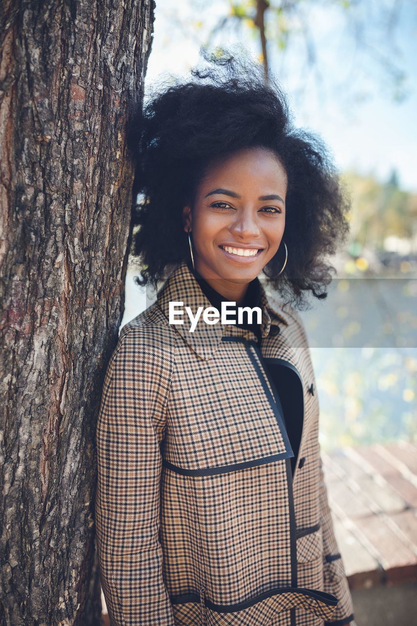 Beautiful african american young woman with afro and large hoop earrings in a stylish coat outdoors