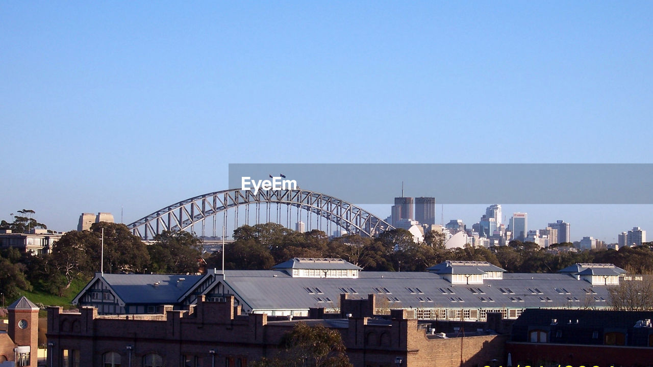 Harbour bridge in city against clear blue sky